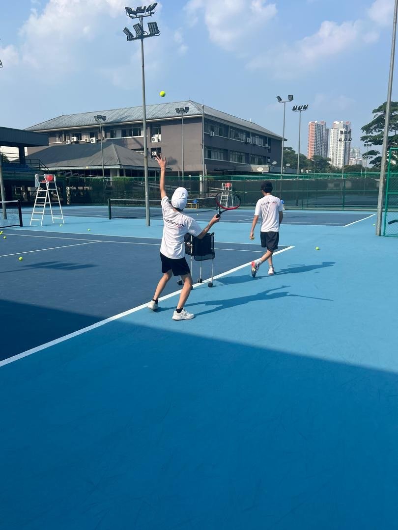 Tennis players practising a serve on an outdoor court